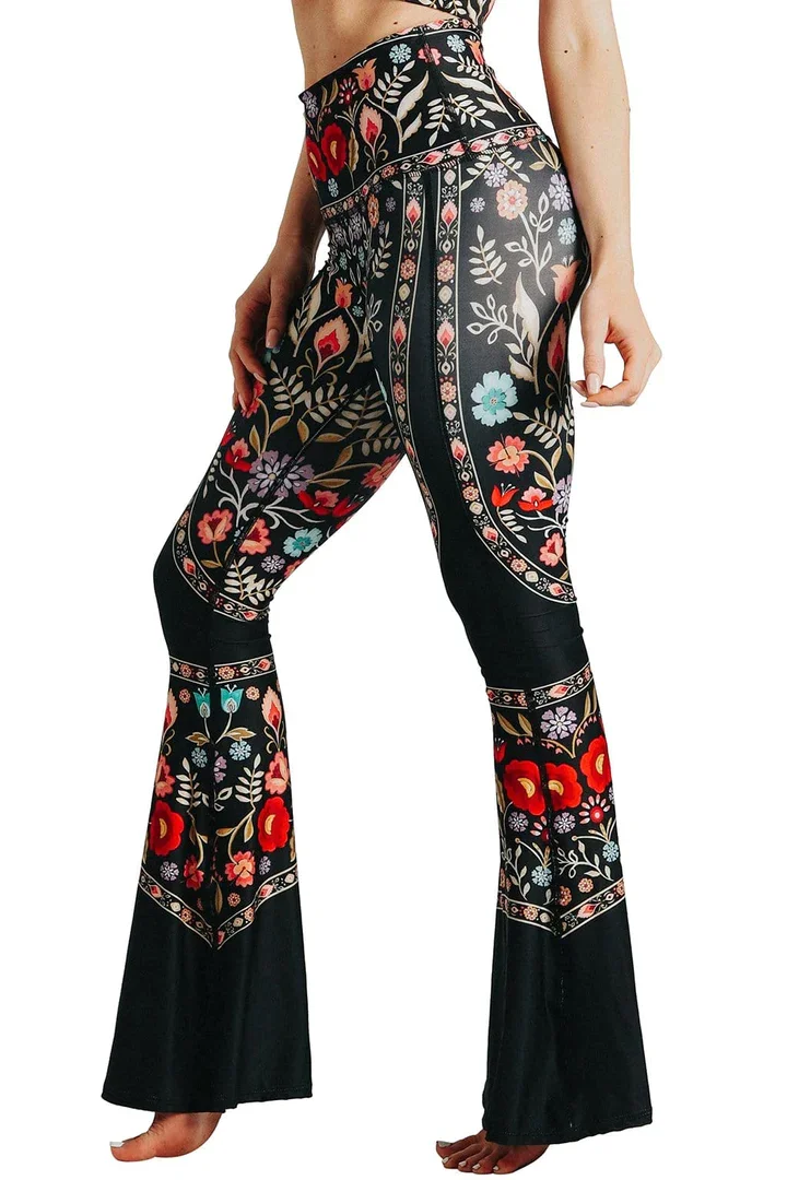 Bottom torso of a woman side view, black yoga pants with decorative pattern.
