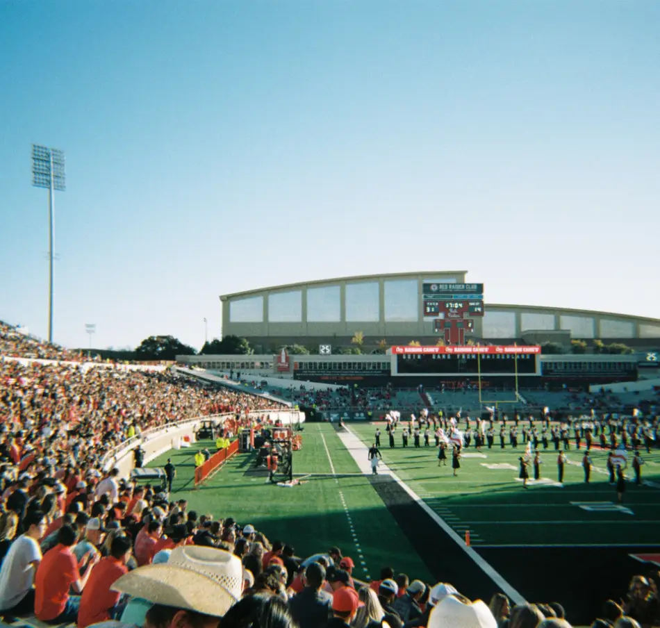 View of a stadium for an American football match. You can see the band on the field and the people in the stands.